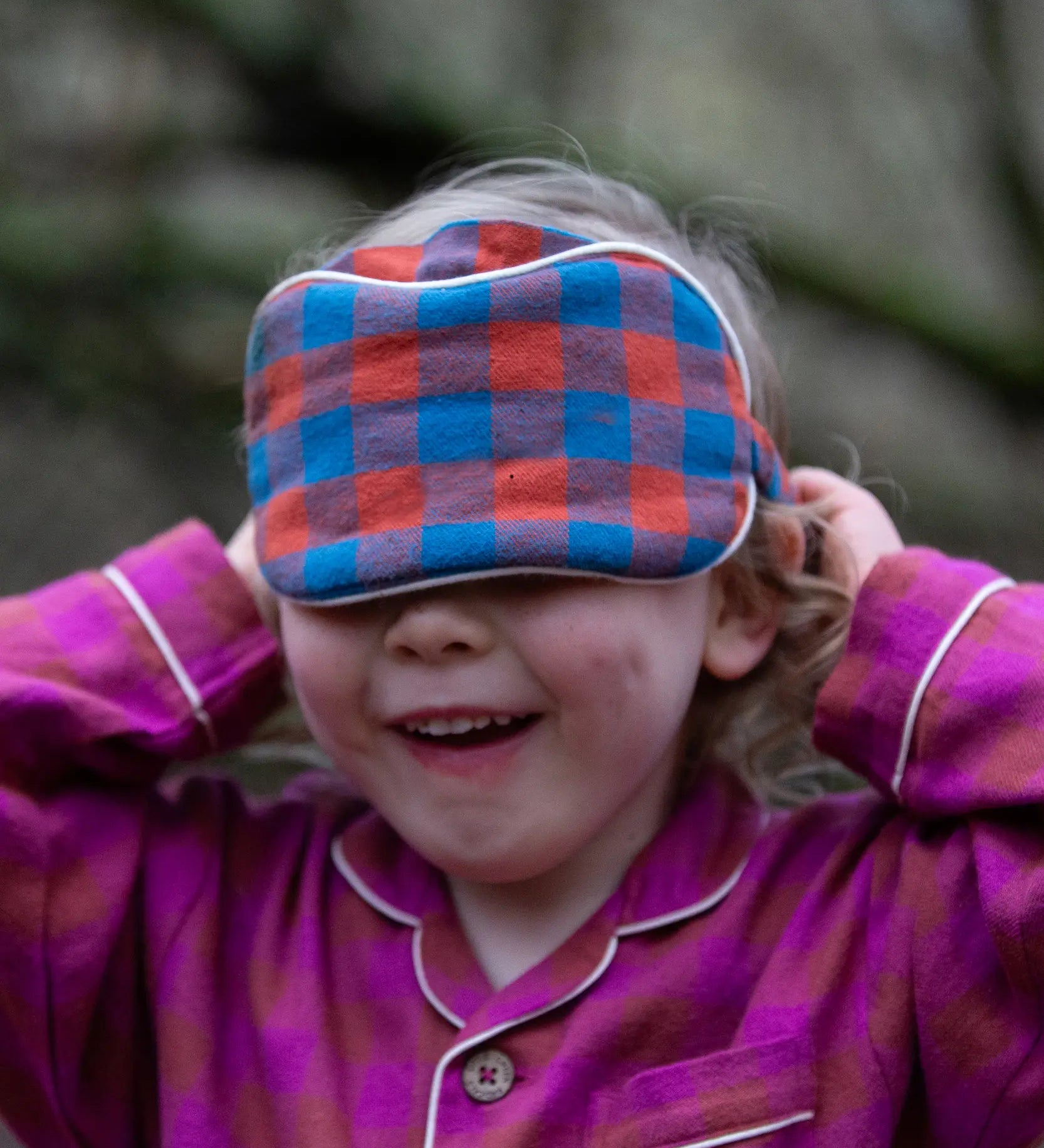 Child holding the Little Green Radicals  burnt ochre blue check organic cotton adult eye mask.