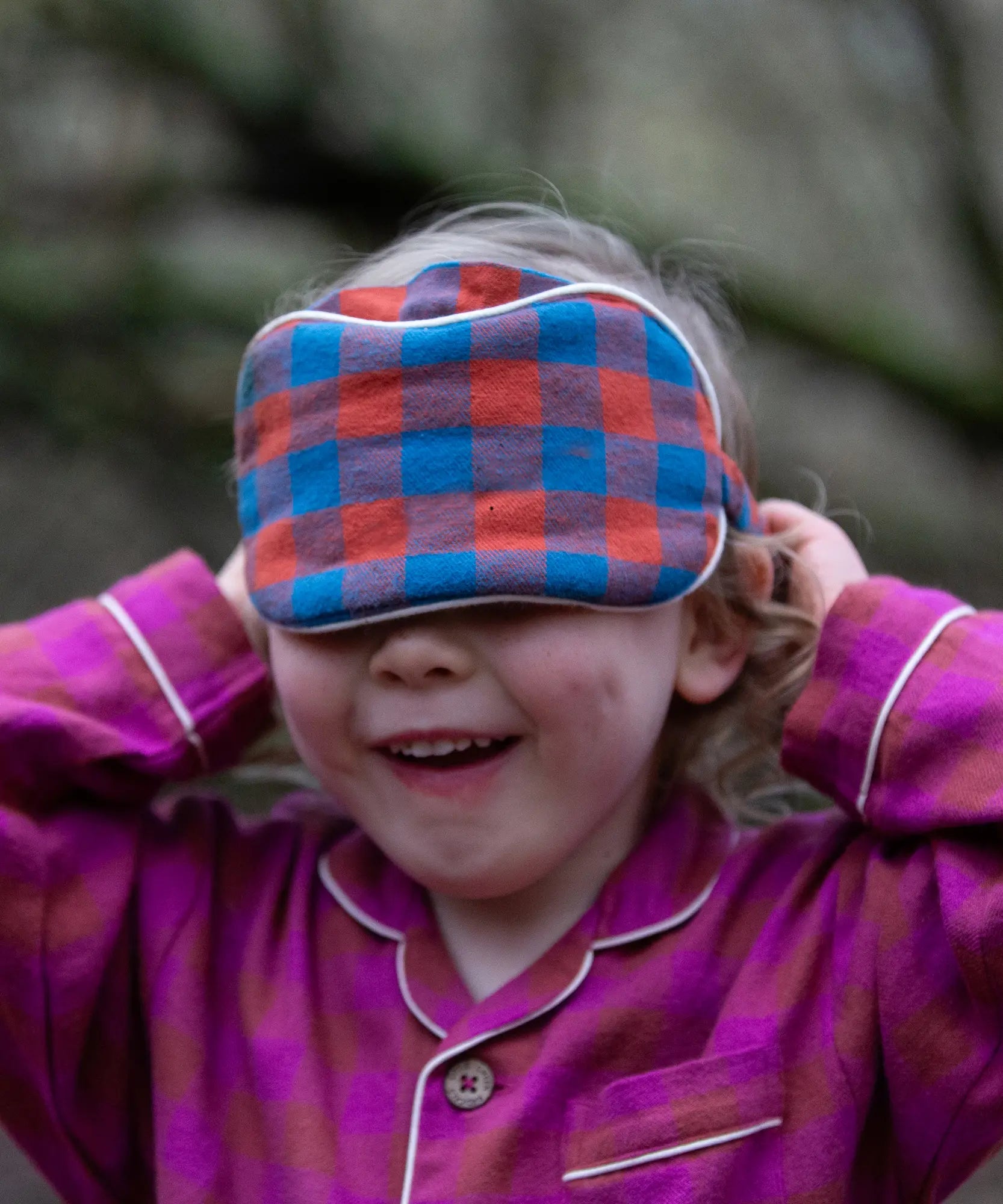 Child holding the Little Green Radicals  burnt ochre blue check organic cotton adult eye mask.