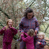 Woman wearing the Little Green Radicals burnt ochre check adult organic cotton classic pyjamas with three children also wearing Little Green Radicals pyjamas. 