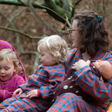 Child wearing the Little Green Radicals burnt ochre check classic pyjamas sitting with an adult wearing the matching pyjamas.