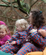 Child wearing the Little Green Radicals burnt ochre check classic pyjamas sitting with an adult wearing the matching pyjamas.