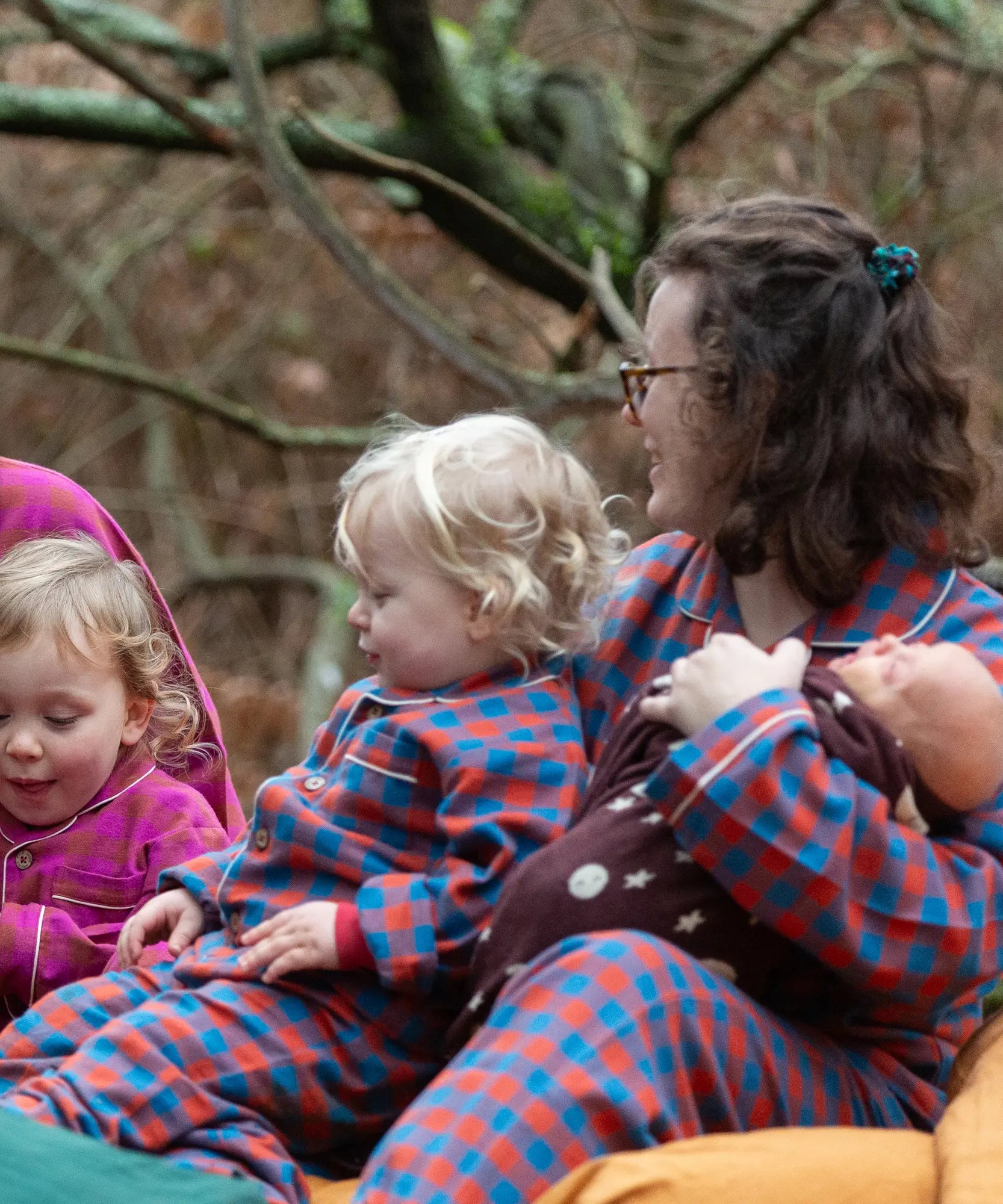 Child wearing the Little Green Radicals burnt ochre check classic pyjamas sitting with an adult wearing the matching pyjamas.