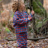 Child wearing the Little Green Radicals burnt ochre check classic pyjamas with yellow gold wellingtons.