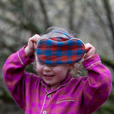 Child holding the Little Green Radicals  burnt ochre blue check organic cotton adult eye mask.