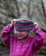 Child holding the Little Green Radicals  burnt ochre blue check organic cotton adult eye mask.