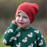 Child wearing Little Green Radicals burnt ochre knitted beanie hat with a green duck knitted jumper. 