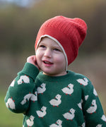 Child wearing Little Green Radicals burnt ochre knitted beanie hat with a green duck knitted jumper. 