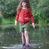 A child wearing a Little Green Radicals From One To Another Burnt Ochre Pointelle Knitted Cardigan with green coloured shorts. Little green Radicals have a wide range of organic cotton, Fairtrade children's clothing and outerwear available here at Babipur.