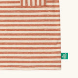 Close up of the green logo tag on the side of the pocket on the Little Green Radicals burnt ochre red striped short sleeve essential organic cotton t-shirt.