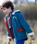 Child wearing a Little Green Radicals calm sea colourblock organic cotton sherpa lined toasty coat with scarf.