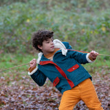 Child wearing a Little Green Radicals calm sea colourblock organic cotton sherpa lined toasty coat with yellow gold trousers.