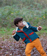 Child wearing a Little Green Radicals calm sea colourblock organic cotton sherpa lined toasty coat with yellow gold trousers.