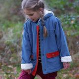Child wearing a Little Green Radicals calm sea colourblock organic cotton sherpa lined toasty coat with polka dot joggers.