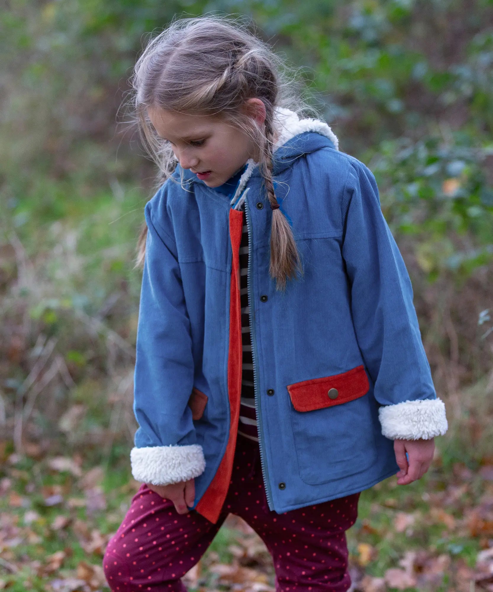 Child wearing a Little Green Radicals calm sea colourblock organic cotton sherpa lined toasty coat with polka dot joggers.