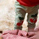 Close up of the red cherry knee appliques on the Little Green Radicals cherry knee patch green cream striped organic cotton joggers being worn with a red t-shirt.