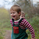 Child wearing the Little Green Radicals berry purple striped long sleeve top with green waterproof rain trousers. 