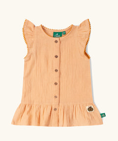 Little Green Radicals coral pink dropped waist children's dress with ochre yellow pom pom ribbon edging on the sleeves and collar.