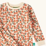 Close up of the Little Green Radicals petals kids organic cotton pyjamas. Cream coloured pyjamas with an all over repeat pink flower print.