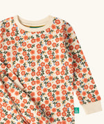 Close up of the Little Green Radicals petals kids organic cotton pyjamas. Cream coloured pyjamas with an all over repeat pink flower print.