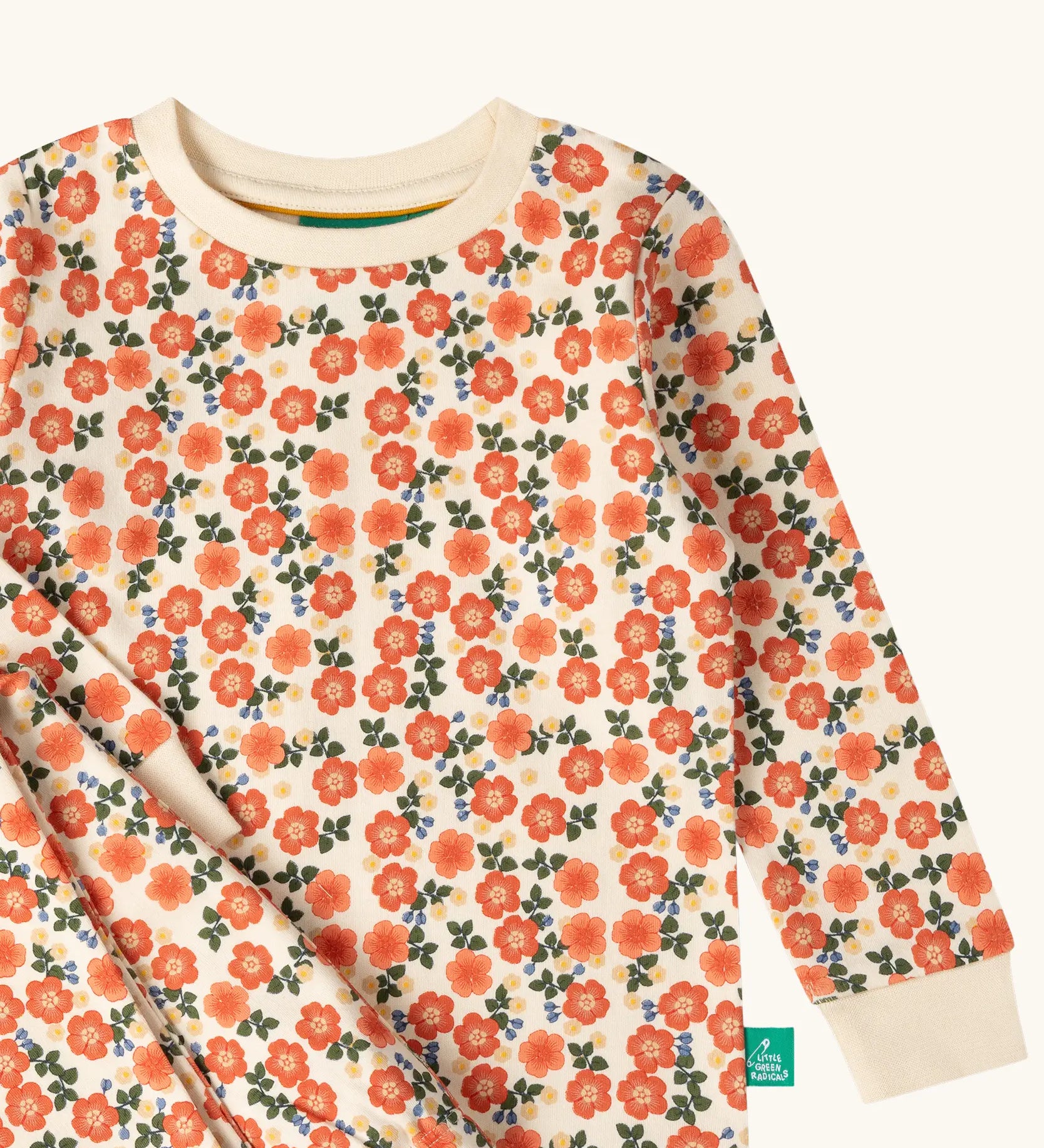 Close up of the Little Green Radicals petals kids organic cotton pyjamas. Cream coloured pyjamas with an all over repeat pink flower print.