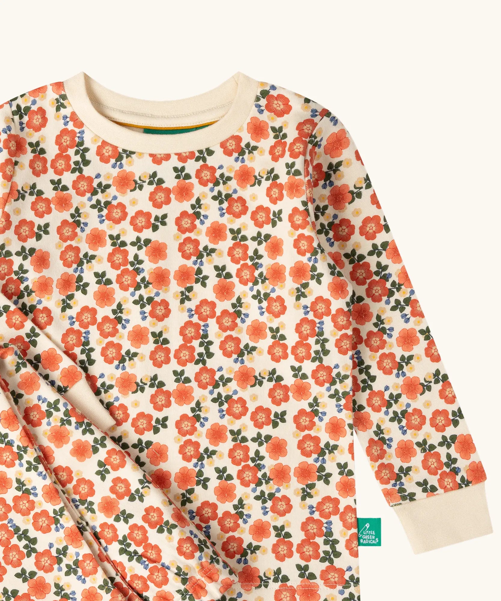 Close up of the Little Green Radicals petals kids organic cotton pyjamas. Cream coloured pyjamas with an all over repeat pink flower print.