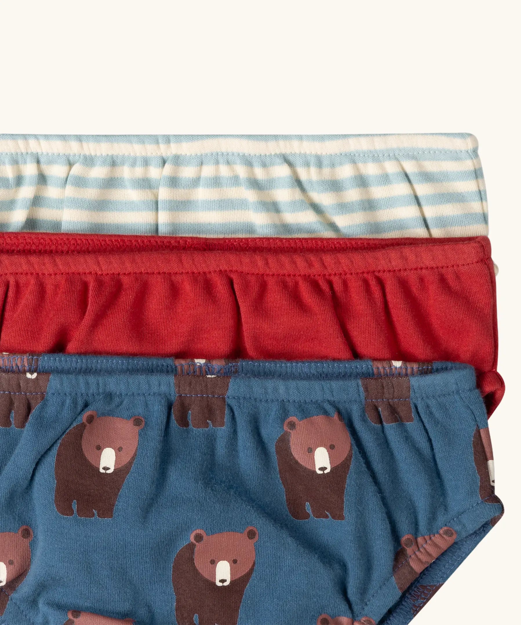 Close up of the elasticated waist on the Little Green Radicals children's organic cotton underwear 3 pack bears design. Brief style pants one navy with a brown bear print, one red and one blue and white stripes. 