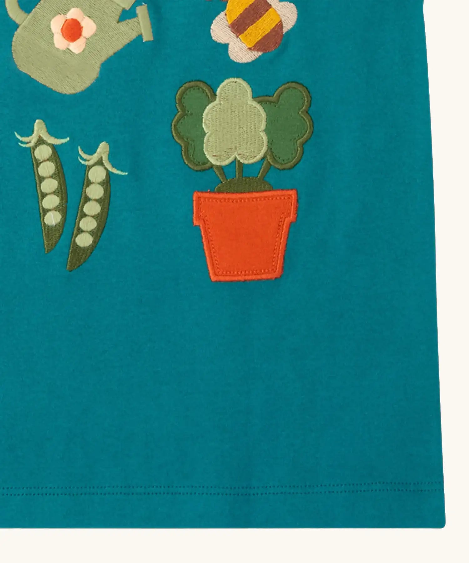 Close up of the hemline on the Little Green Radicals kids Spring garden embroidered organic cotton green t-shirt. 