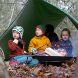Three children sitting by a campfire wearing Little green Radicals knitwear and hats. These organic cotton clothing and accessories are part of a wide range available here at Babipur. 