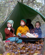 Three children sitting by a campfire wearing Little green Radicals knitwear and hats. These organic cotton clothing and accessories are part of a wide range available here at Babipur. 
