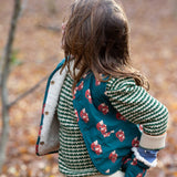 A child wearing the Little Green Radicals Children's Sherpa Fleece Gilet in the red foxes design. This gilet is a part of a wide range of organic cotton clothing for children available here at Babipur. 