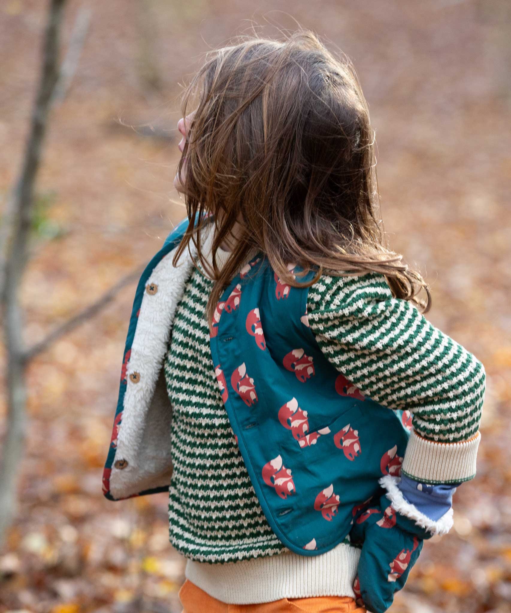 A child wearing the Little Green Radicals Children's Sherpa Fleece Gilet in the red foxes design. This gilet is a part of a wide range of organic cotton clothing for children available here at Babipur. 