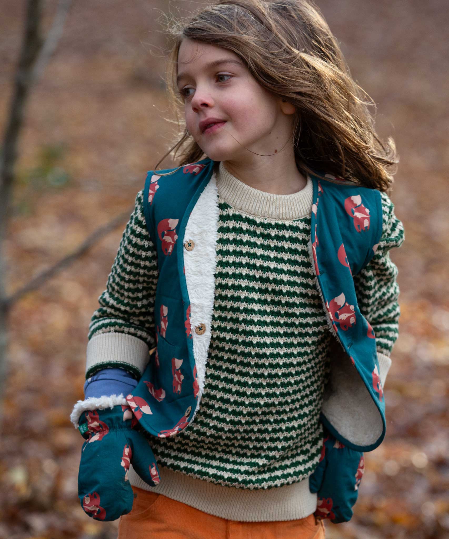 A child wearing the Little Green Radicals Children's Sherpa Fleece Gilet in the red foxes design. This gilet is a part of a wide range of organic cotton clothing for children available here at Babipur. 