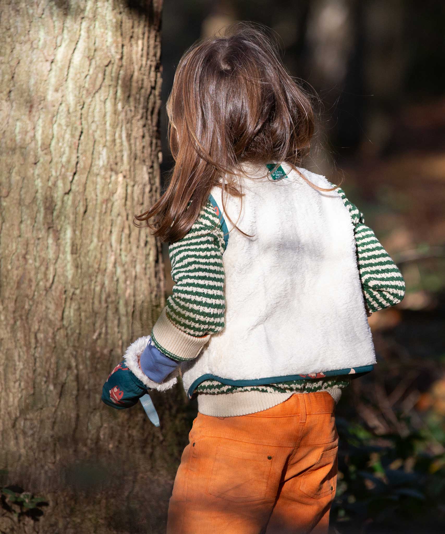 A child wearing the Little Green Radicals Children's Sherpa Fleece Gilet in the red foxes design. This gilet is a part of a wide range of organic cotton clothing for children available here at Babipur. 
