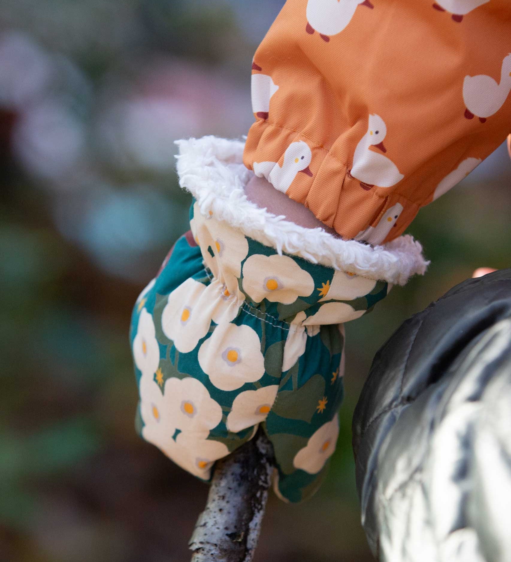 A close up of the Little Green Radicals Hedgerow print Children's Sherpa Lined Mittens on a child's hand. 
