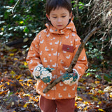A child holding a stick wearing the  Little Green Radicals Hedgerow print Children's Sherpa Lined Mittens and a duck print coat. 