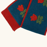 Close up of the Little Green Radicals tulips knitted blue scarf. Blue scarf with red tulips and red trim.