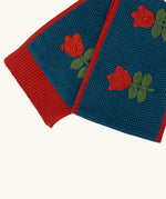 Close up of the Little Green Radicals tulips knitted blue scarf. Blue scarf with red tulips and red trim.