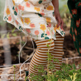 Close up of child's legs wearing the Little Green Radicals apricot gold striped organic cotton leggings.