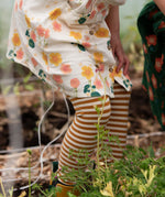 Close up of child's legs wearing the Little Green Radicals apricot gold striped organic cotton leggings.