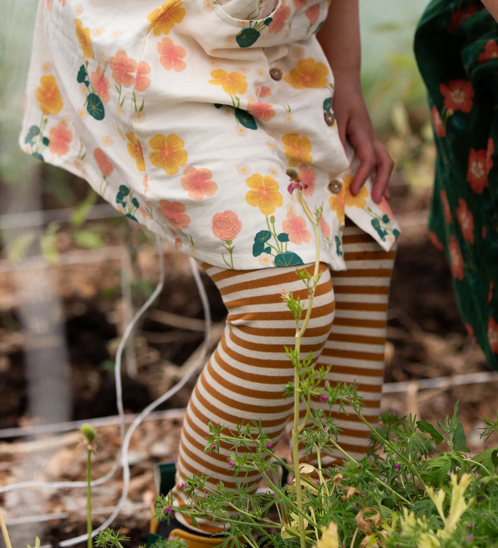 Close up of child's legs wearing the Little Green Radicals apricot gold striped organic cotton leggings.