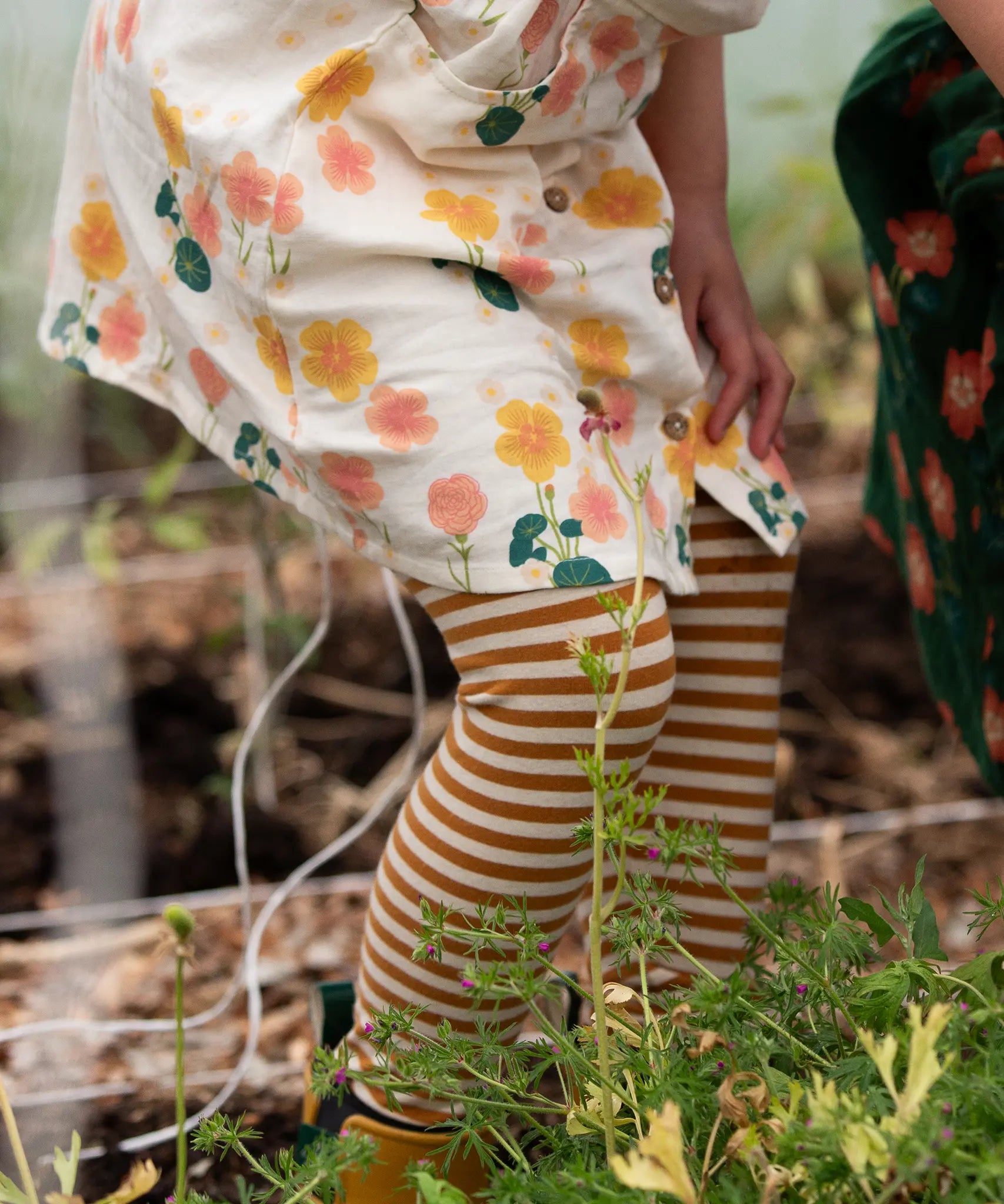 Close up of child's legs wearing the Little Green Radicals apricot gold striped organic cotton leggings.