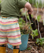 Back of the Little Green Radicals children's cream rainbow striped by the sea twill shorts being worn.