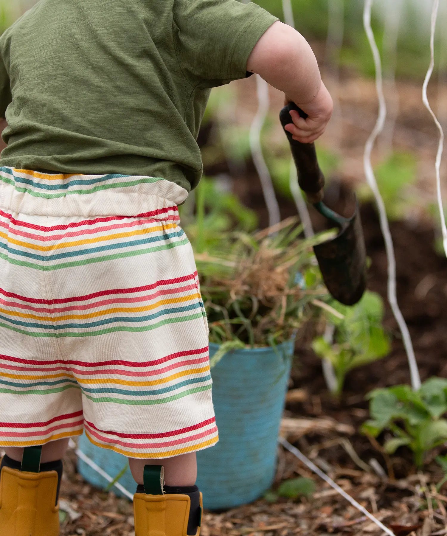 Back of the Little Green Radicals children's cream rainbow striped by the sea twill shorts being worn.