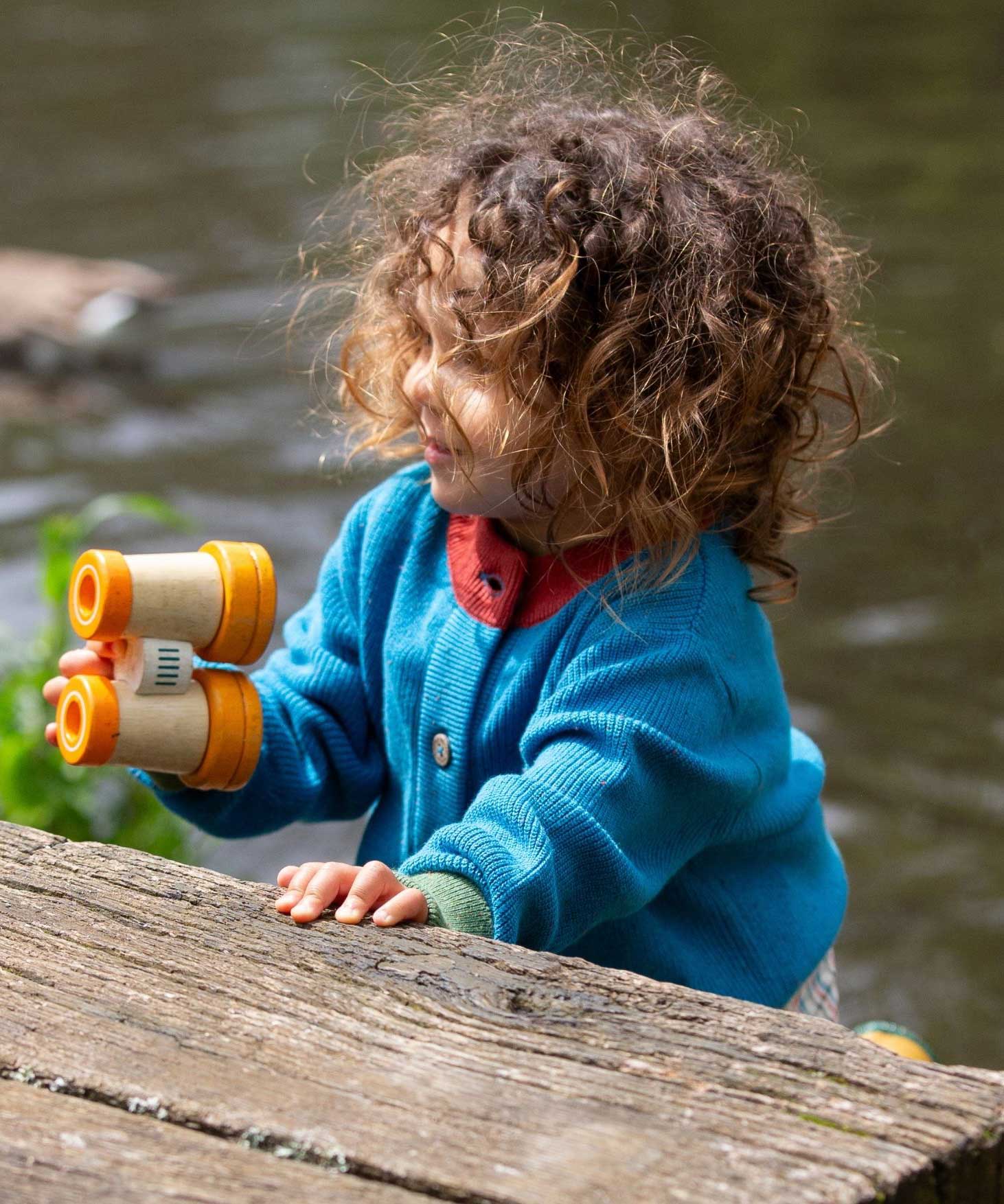 A child wearing the Little Green Radicals From One To Another Deep Blue Colour Block Knitted Cardigan. This organic cotton cardigan is part of a wide range of organic cotton, Fairtrade children's clothing and outerwear available here at Babipur.