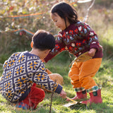Children wearing Little Green Radicals organic cotton knitted jumpers. One has a folk birds design the other has a  tile pattern knit.