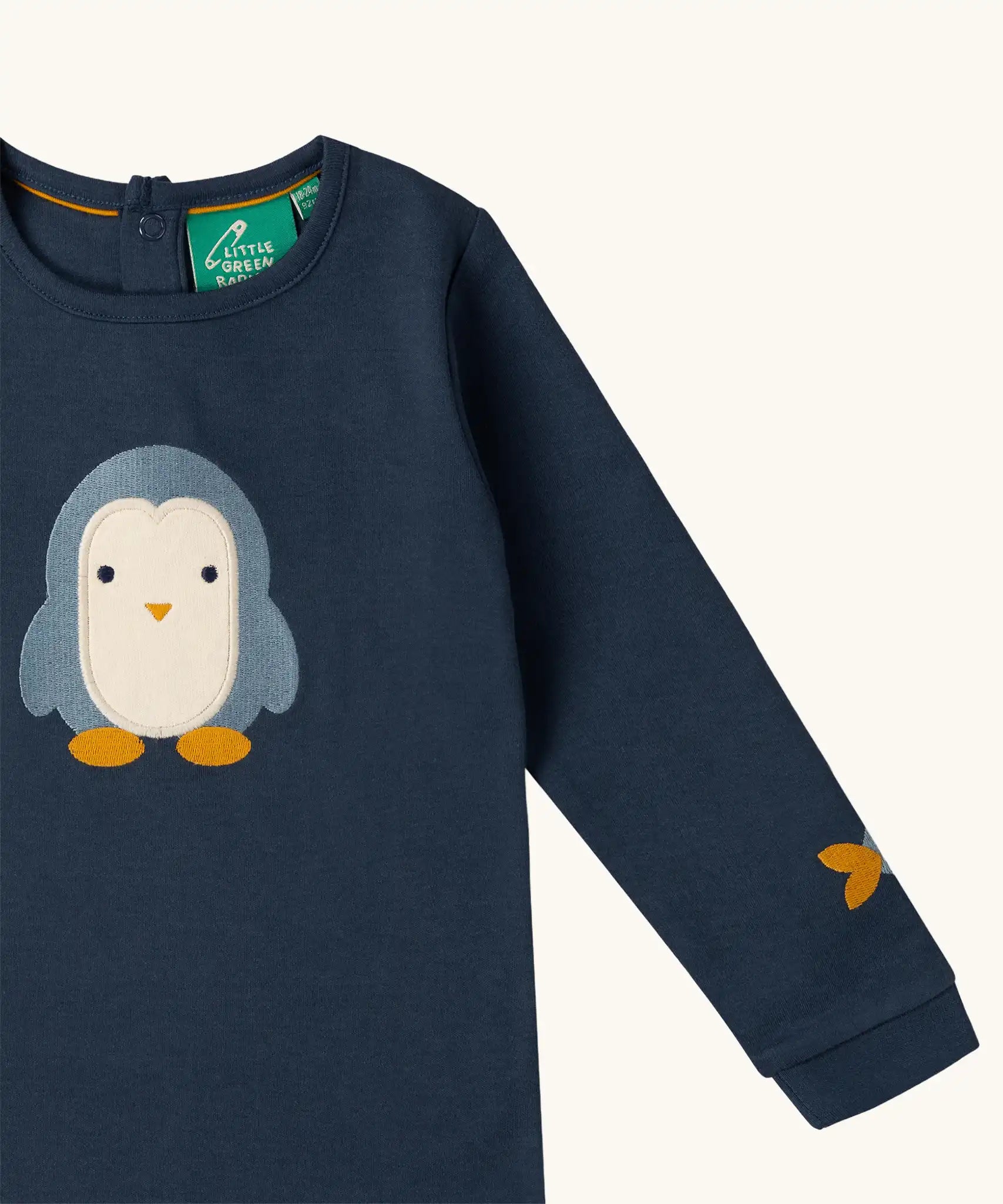 Close up of the Little Green Radicals blue penguins applique long sleeve organic cotton top in navy.