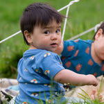 A child wearing the Little Green Radicals Kids' Organic T-shirt and Joggers Playset outfit in the  Blue Rainbows design. 