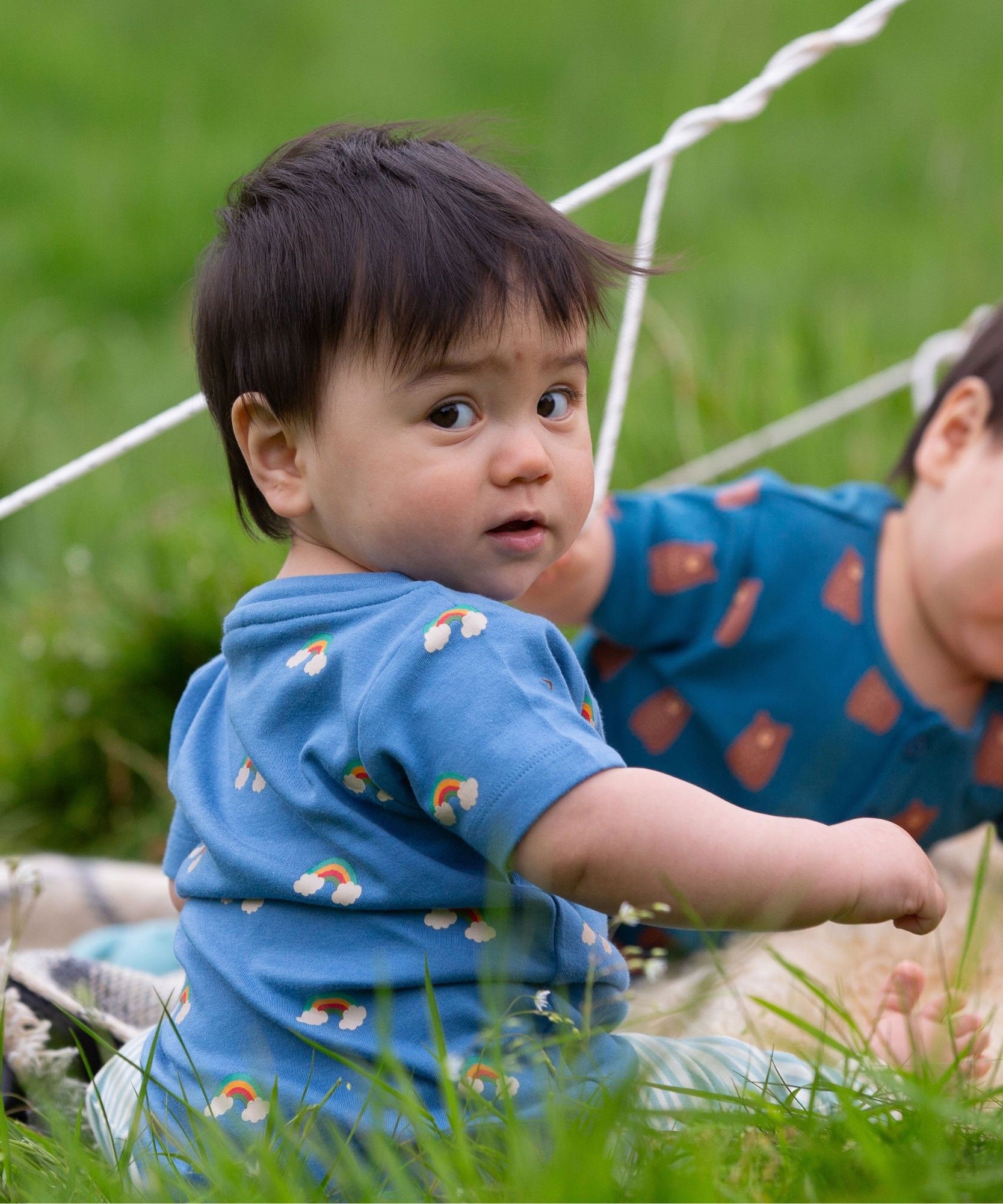 A child wearing the Little Green Radicals Kids' Organic T-shirt and Joggers Playset outfit in the  Blue Rainbows design. 