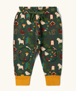 Little Green Radicals cosy organic cotton knee patch joggers with a woodland design print. Dark green joggers with a woodland print featuring animals, trees a hut.