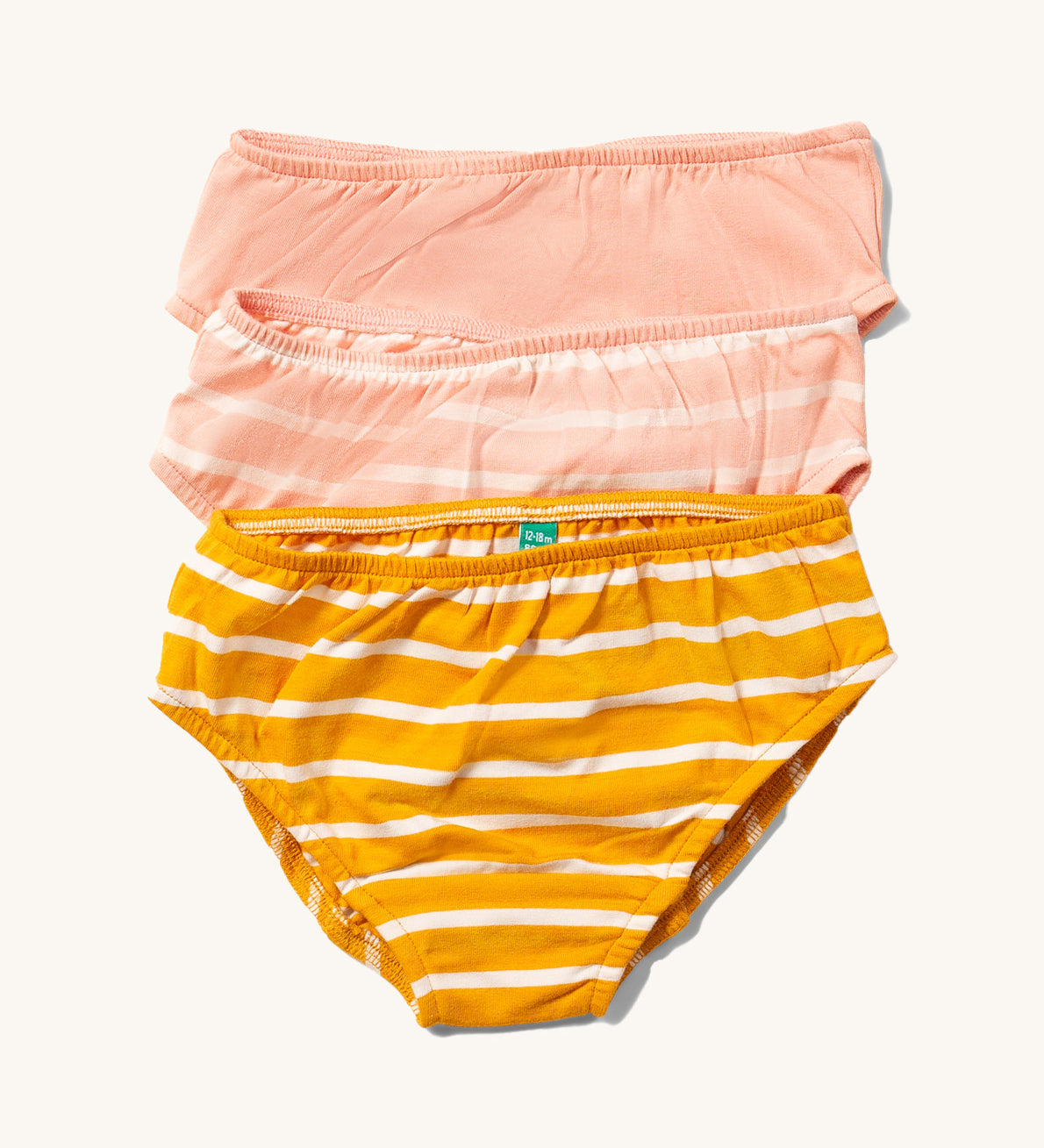 Little Green Radicals Kids Organic Cotton Briefs Set in a 3 Pack. One pair is striped yellow gold, one is pink striped and one is plain pink.